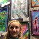 Student standing next to their artwork